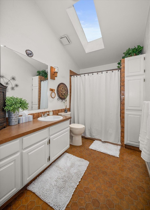 bathroom featuring vanity, toilet, vaulted ceiling with skylight, and tile patterned flooring