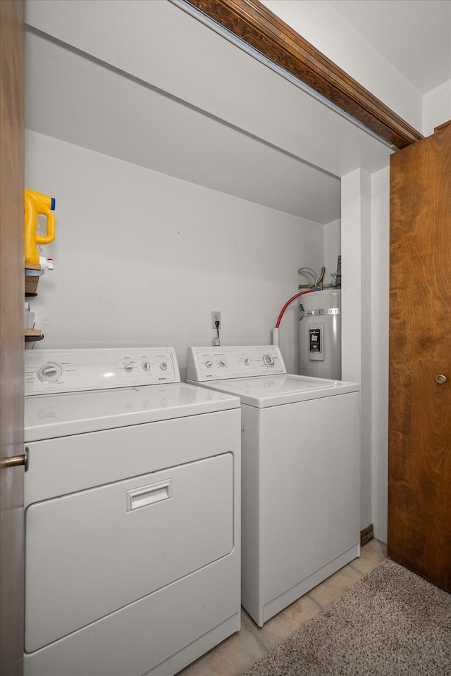 laundry area featuring strapped water heater, light tile patterned flooring, and washing machine and clothes dryer