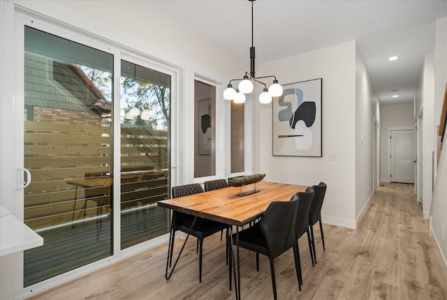 dining room with light hardwood / wood-style floors and a notable chandelier