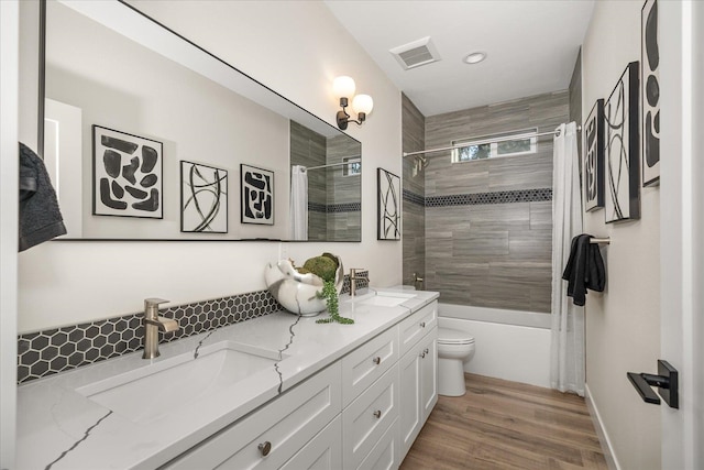 full bathroom with tasteful backsplash, wood-type flooring, shower / tub combo, toilet, and vanity