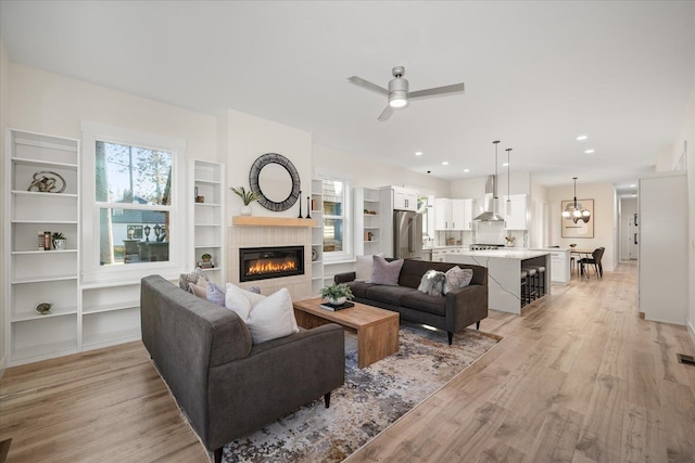 living room with light hardwood / wood-style floors and ceiling fan with notable chandelier