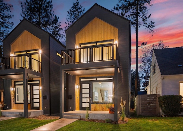 contemporary home featuring a lawn and a balcony