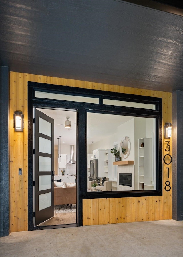 interior space with wall chimney exhaust hood, wooden walls, and concrete flooring