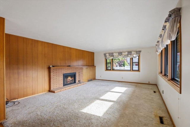 unfurnished living room featuring light carpet, a brick fireplace, and wood walls