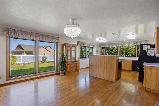 kitchen featuring light wood-type flooring, a textured ceiling, a chandelier, and plenty of natural light