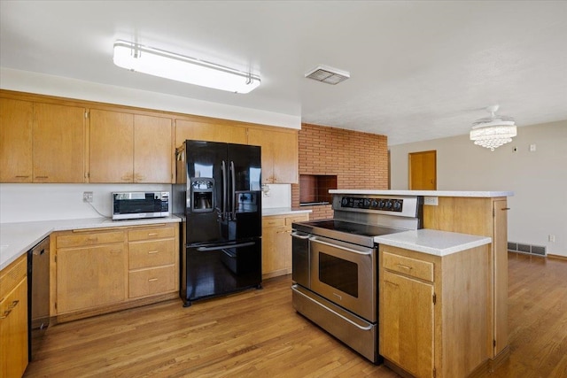 kitchen with black appliances, light hardwood / wood-style flooring, and a kitchen island