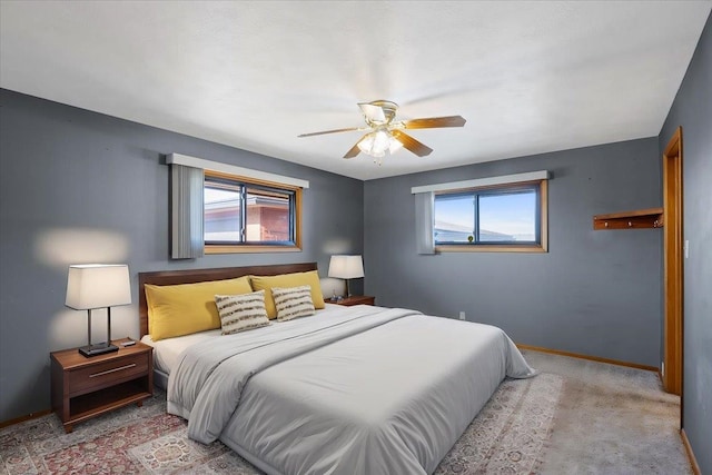 carpeted bedroom featuring multiple windows and ceiling fan