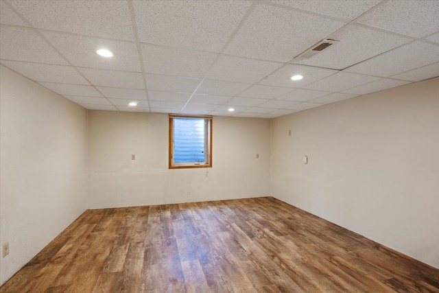 empty room featuring a drop ceiling and hardwood / wood-style floors