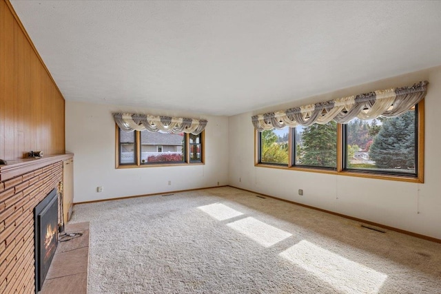 unfurnished living room with light carpet, a textured ceiling, and wooden walls