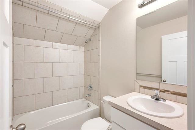 full bathroom with toilet, tiled shower / bath combo, vanity, and vaulted ceiling