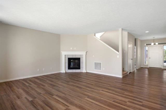 unfurnished living room featuring a textured ceiling, a fireplace, and dark hardwood / wood-style flooring