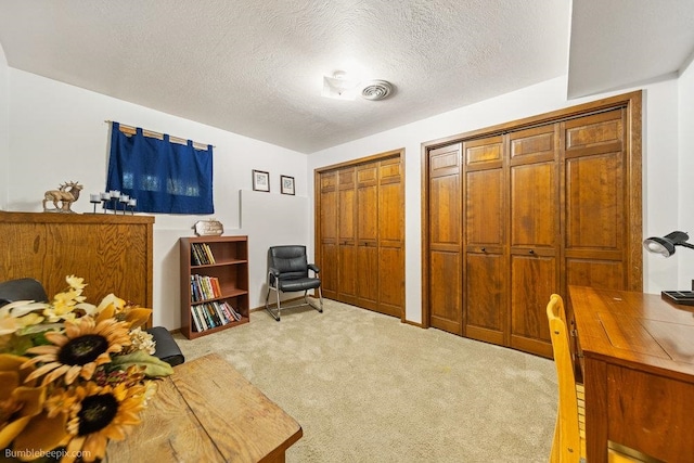 interior space featuring a textured ceiling, two closets, and light colored carpet