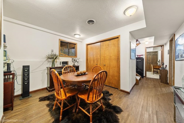 dining area featuring a textured ceiling and light wood-type flooring