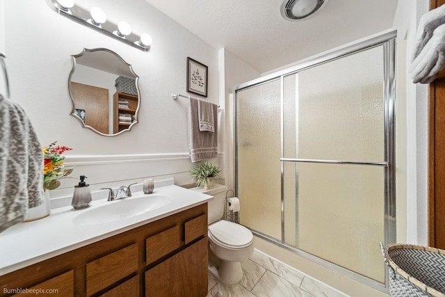 bathroom featuring toilet, vanity, and a shower with door