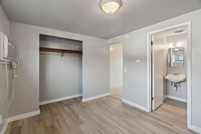 unfurnished bedroom featuring a closet, ensuite bathroom, and light hardwood / wood-style flooring