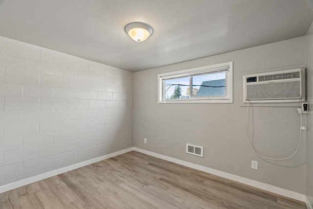 spare room featuring a wall unit AC and light wood-type flooring