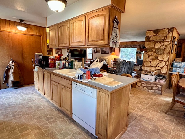 kitchen featuring kitchen peninsula, dishwasher, sink, and wood walls