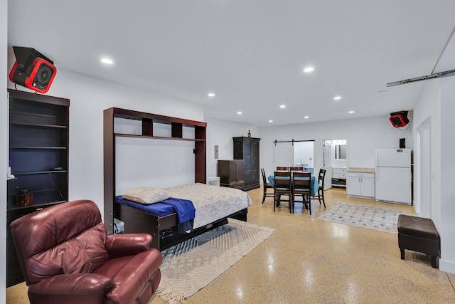 bedroom with white fridge and a barn door