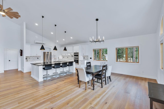 dining room featuring sink, high vaulted ceiling, light hardwood / wood-style flooring, and ceiling fan with notable chandelier