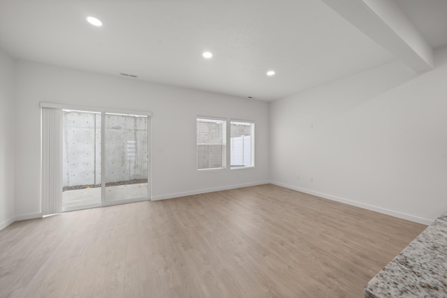 unfurnished room with light hardwood / wood-style flooring and beam ceiling