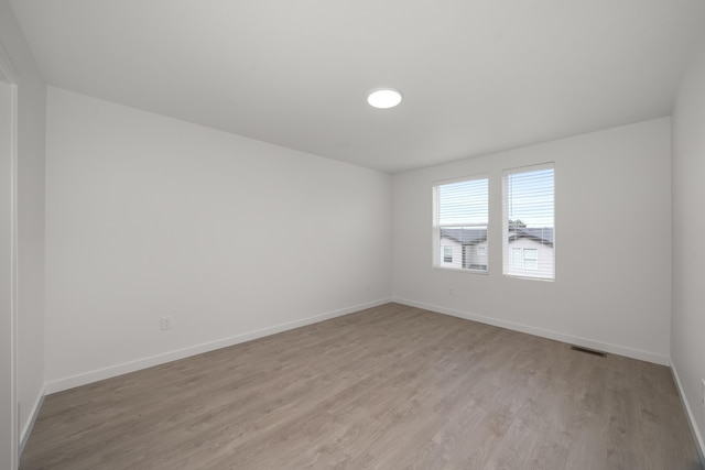 spare room with baseboards, visible vents, and light wood-type flooring