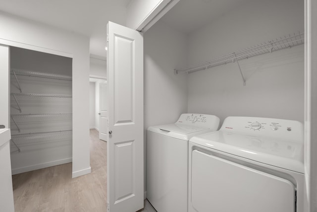 clothes washing area featuring laundry area, light wood-type flooring, and washer and dryer