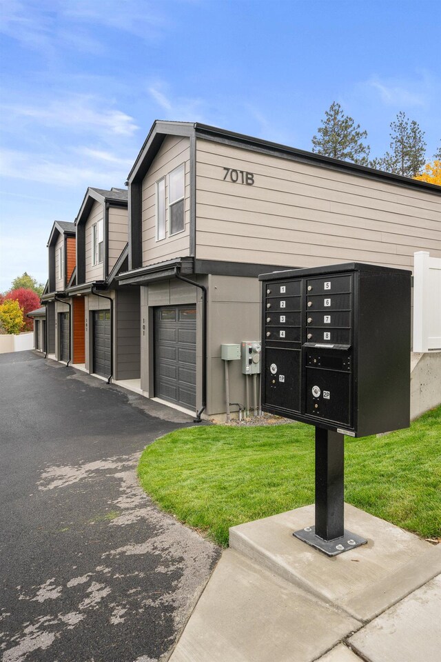 view of home's community with an attached garage, aphalt driveway, and mail area