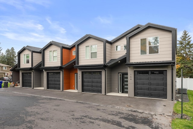 view of front of property with an attached garage, fence, and cooling unit