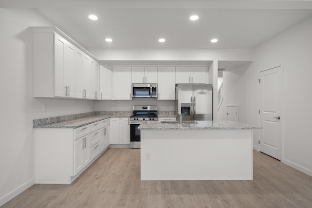 kitchen featuring appliances with stainless steel finishes, baseboards, light wood finished floors, and white cabinetry