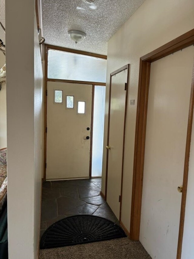 doorway featuring a textured ceiling and dark carpet