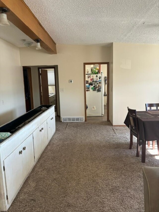 carpeted dining space featuring a textured ceiling, ceiling fan, and beam ceiling