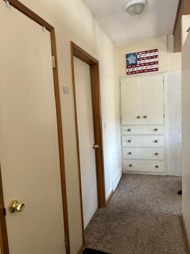 corridor with a textured ceiling and carpet flooring