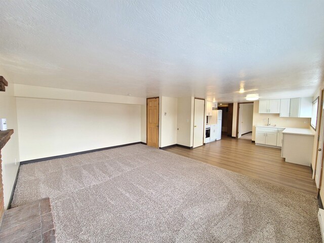 unfurnished living room with hardwood / wood-style flooring, a textured ceiling, and sink