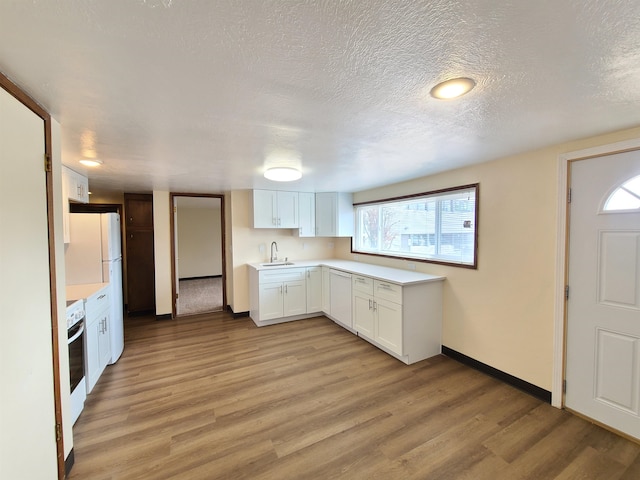 kitchen featuring white cabinetry, sink, light hardwood / wood-style flooring, and a textured ceiling