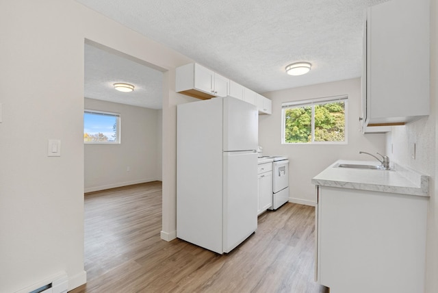 kitchen featuring sink, stove, white cabinets, light hardwood / wood-style flooring, and white refrigerator