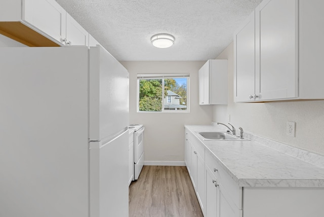 kitchen featuring sink, light wood-type flooring, white cabinets, a textured ceiling, and white appliances