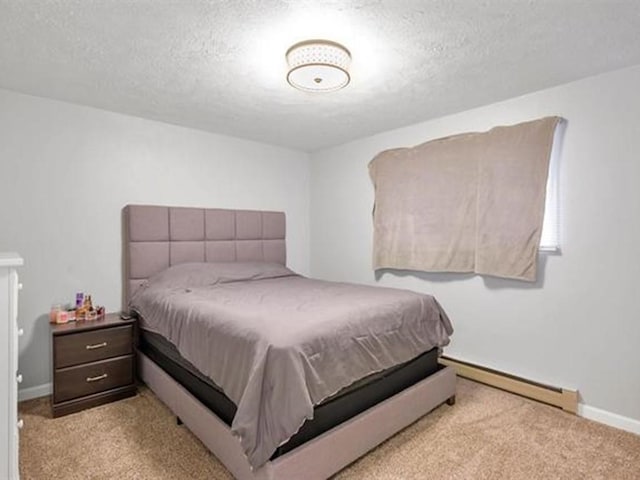 carpeted bedroom featuring baseboard heating and a textured ceiling