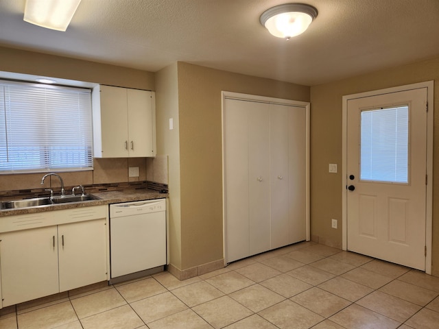 kitchen featuring white cabinetry, sink, white dishwasher, and light tile patterned floors