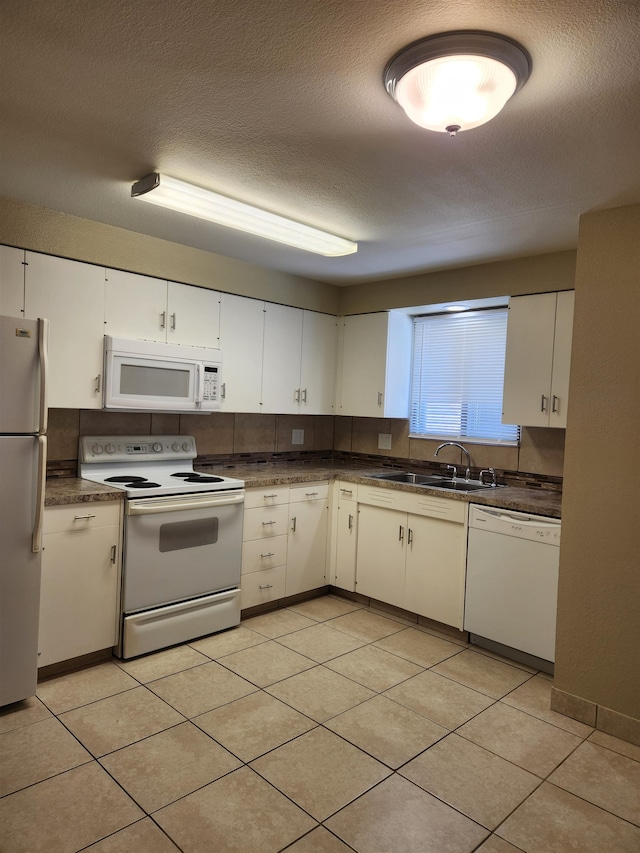 kitchen with white appliances, a textured ceiling, white cabinetry, and sink