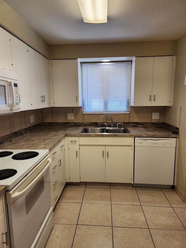 kitchen with white appliances, light tile patterned flooring, sink, a textured ceiling, and white cabinetry