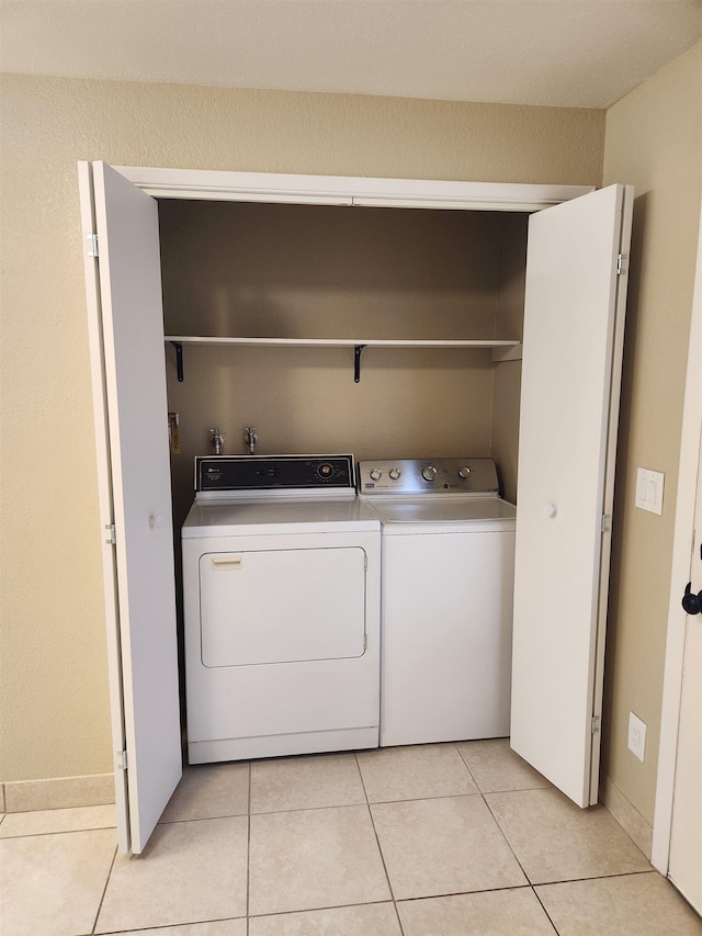 laundry area with washer and dryer and light tile patterned floors