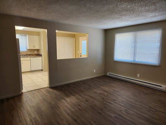 spare room featuring light hardwood / wood-style flooring, a baseboard heating unit, sink, and a textured ceiling