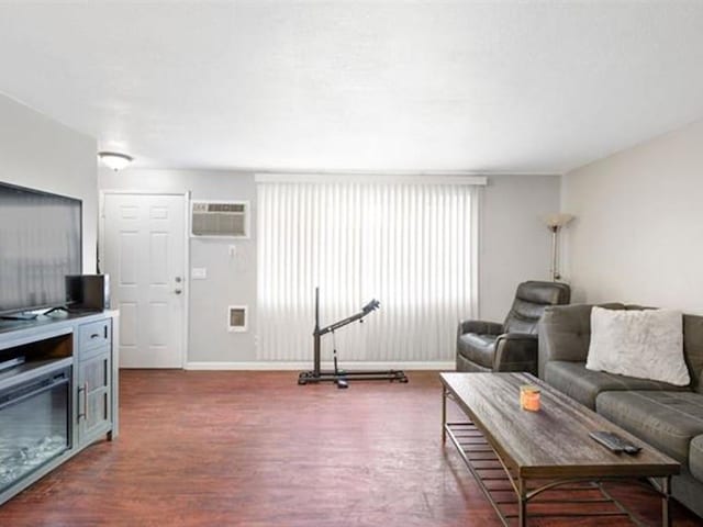 living room featuring a wall mounted AC and dark hardwood / wood-style flooring