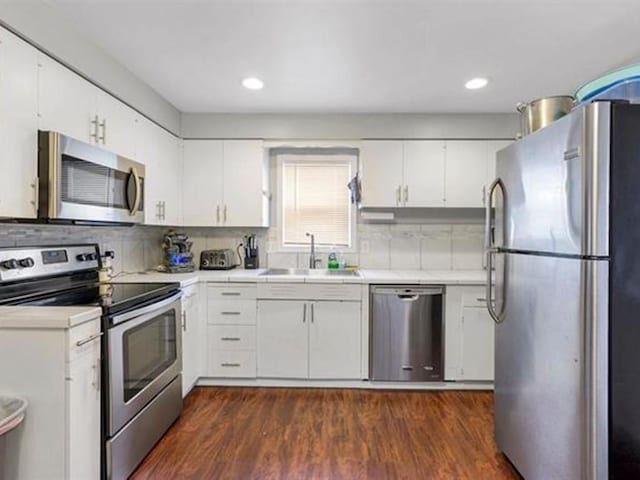 kitchen featuring appliances with stainless steel finishes, white cabinetry, sink, and dark hardwood / wood-style floors