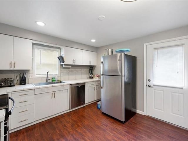 kitchen with decorative backsplash, dark wood-type flooring, stainless steel appliances, sink, and white cabinetry