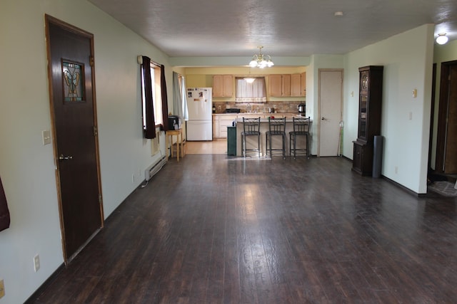 interior space with dark wood-style floors, freestanding refrigerator, light countertops, decorative backsplash, and a chandelier