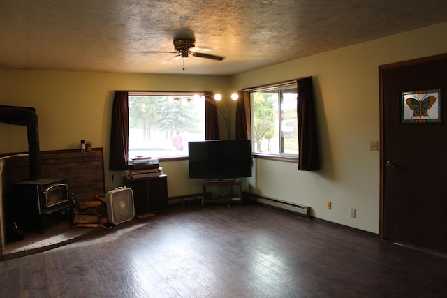 unfurnished living room featuring wood finished floors, a wood stove, a ceiling fan, and a textured ceiling