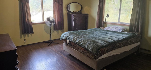 bedroom with dark wood-style floors, baseboard heating, and baseboards