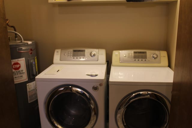 clothes washing area with independent washer and dryer, laundry area, and water heater