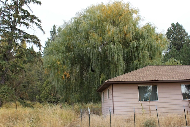 view of home's exterior featuring a forest view and roof with shingles